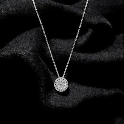 Silver necklace with a round pendant on a black fabric background