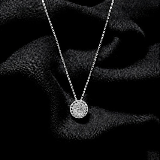 Silver necklace with a round pendant on a black fabric background