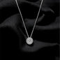 Silver necklace with a round pendant on a black fabric background